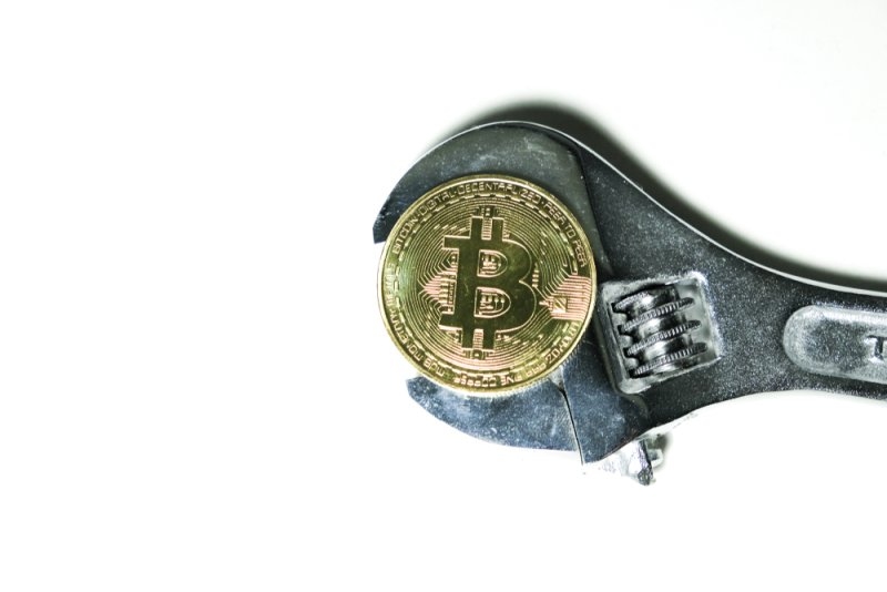 A wrench holding a bitcoin 