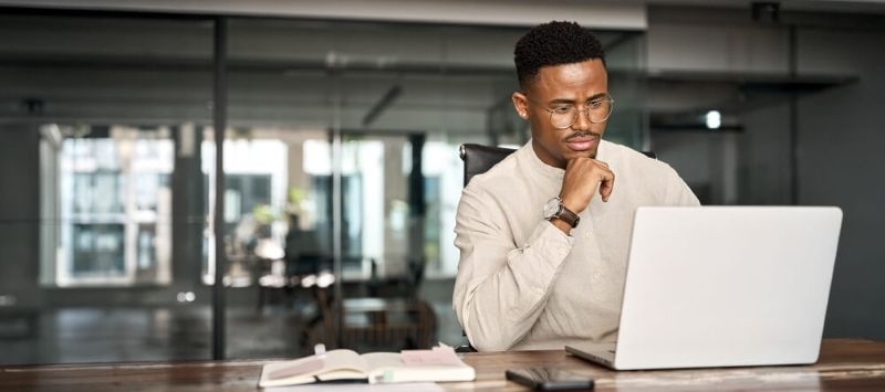  young male businessman looking at computer thinking on online investment on laptop working at office.