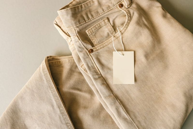 air of beige pants with a white hanger on a neutral background